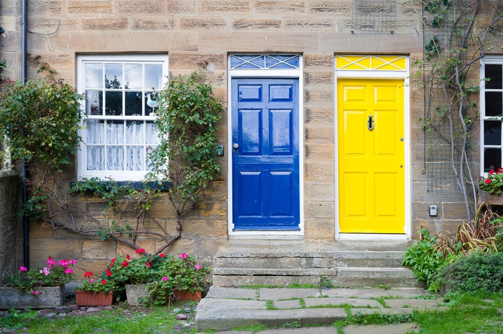 a light blue and light yellow front door side by side on a semi-detached property